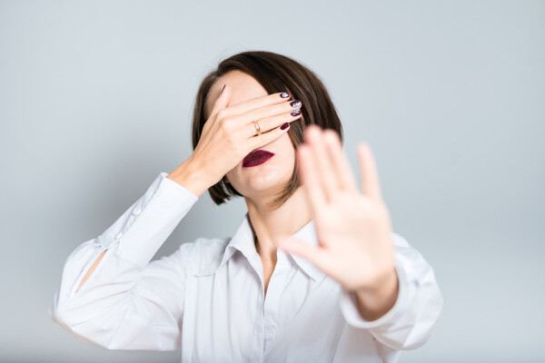 Woman covering face with one hand and holding out other hand to indicate stop signal in regards to seeing too many fonts