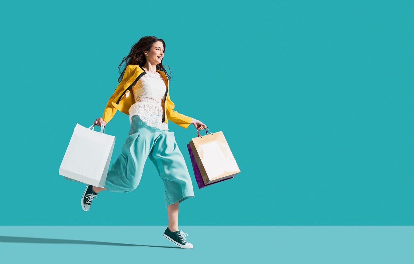 Woman jumping with shopping bag in each hand representing potential buyer persona