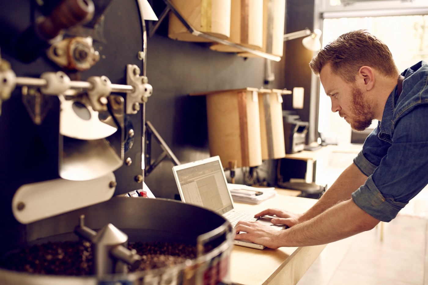Man who owns small coffee business uses laptop to work on digital marketing