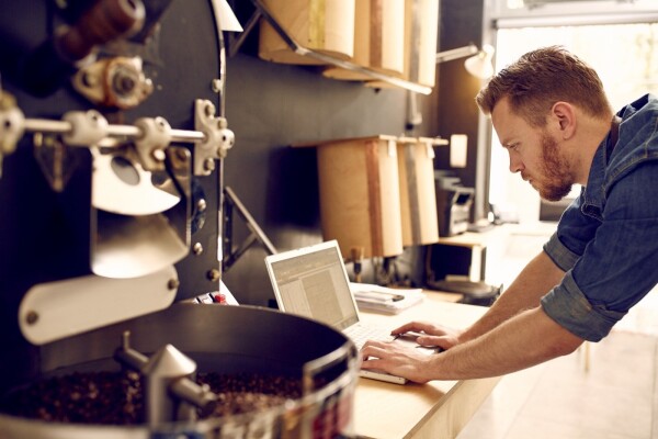 Man who owns small coffee business uses laptop to work on digital marketing