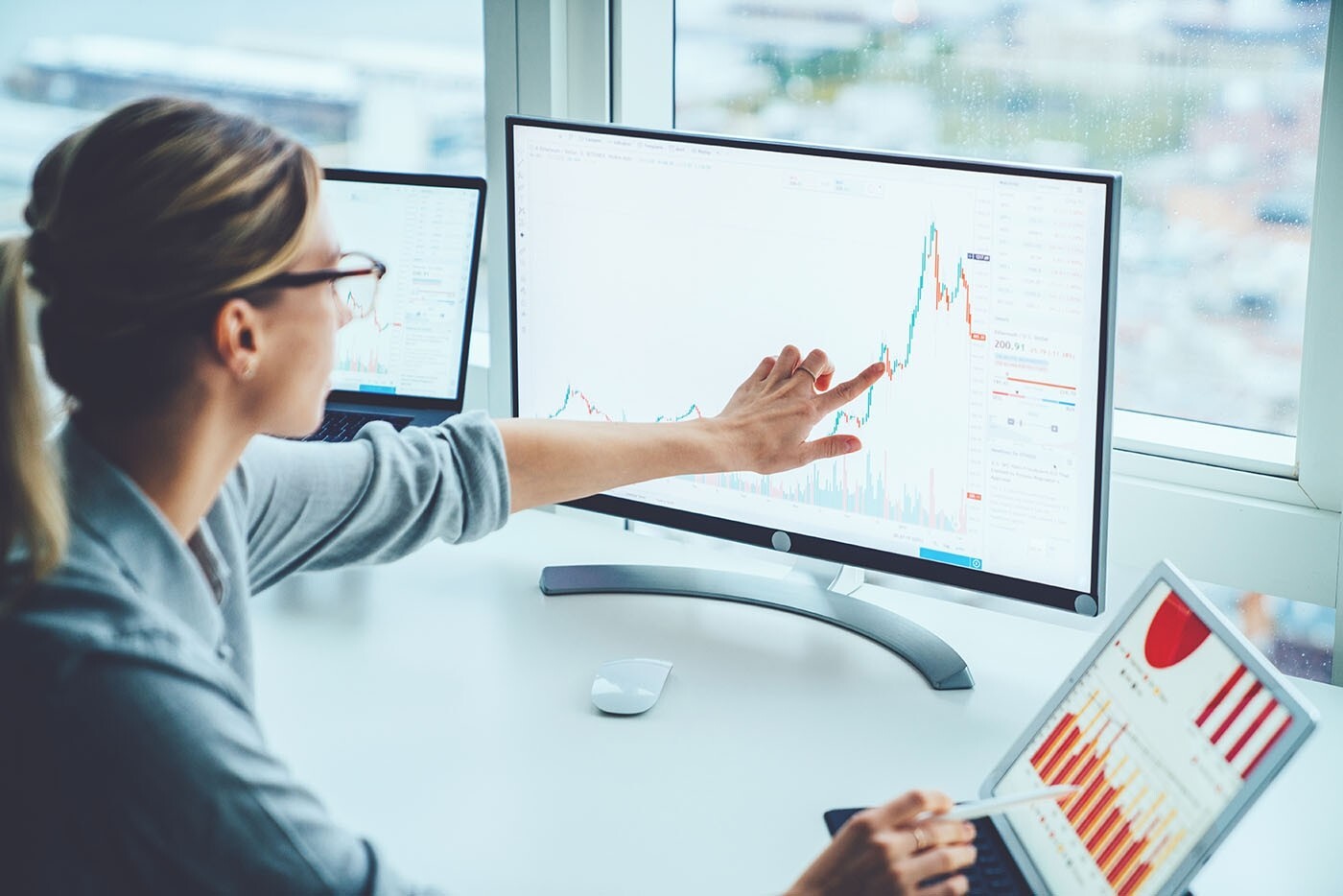 Woman looking at data on desktop screen and on tablet