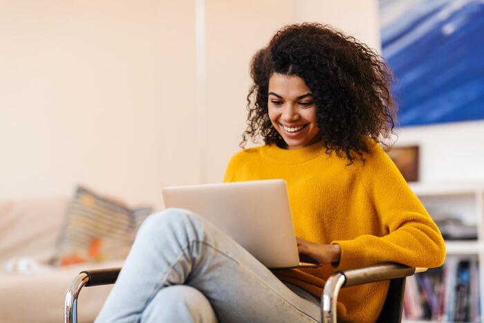 Woman browsing the web on laptop while sitting in a chair