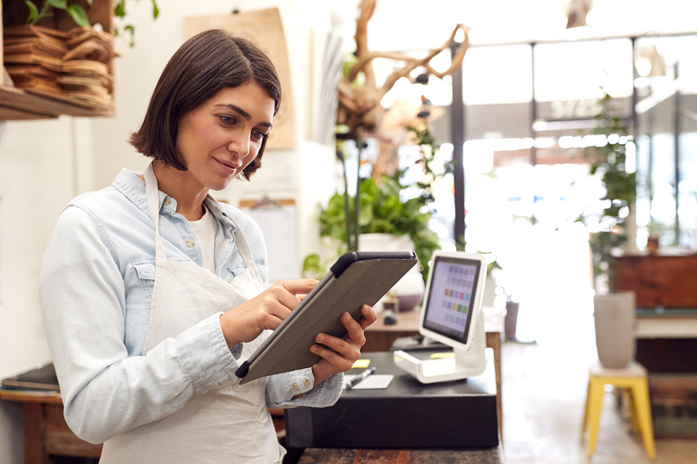 Woman wearing an apron, using a tablet with electronic kiosk to keep track of offline conversions