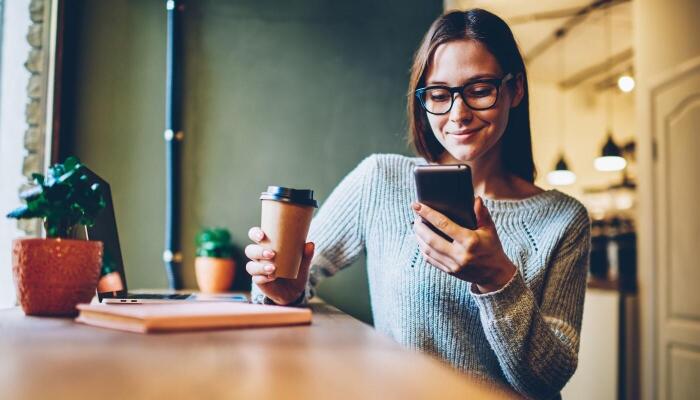 Woman browsing mobile-friendly site on her phone in a coffee shop