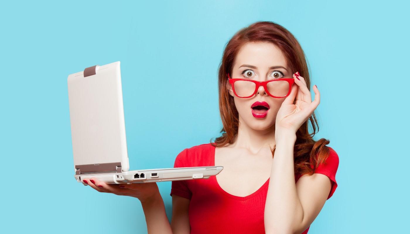 Woman pulling down glasses in awe while looking at improved search rankings on laptop
