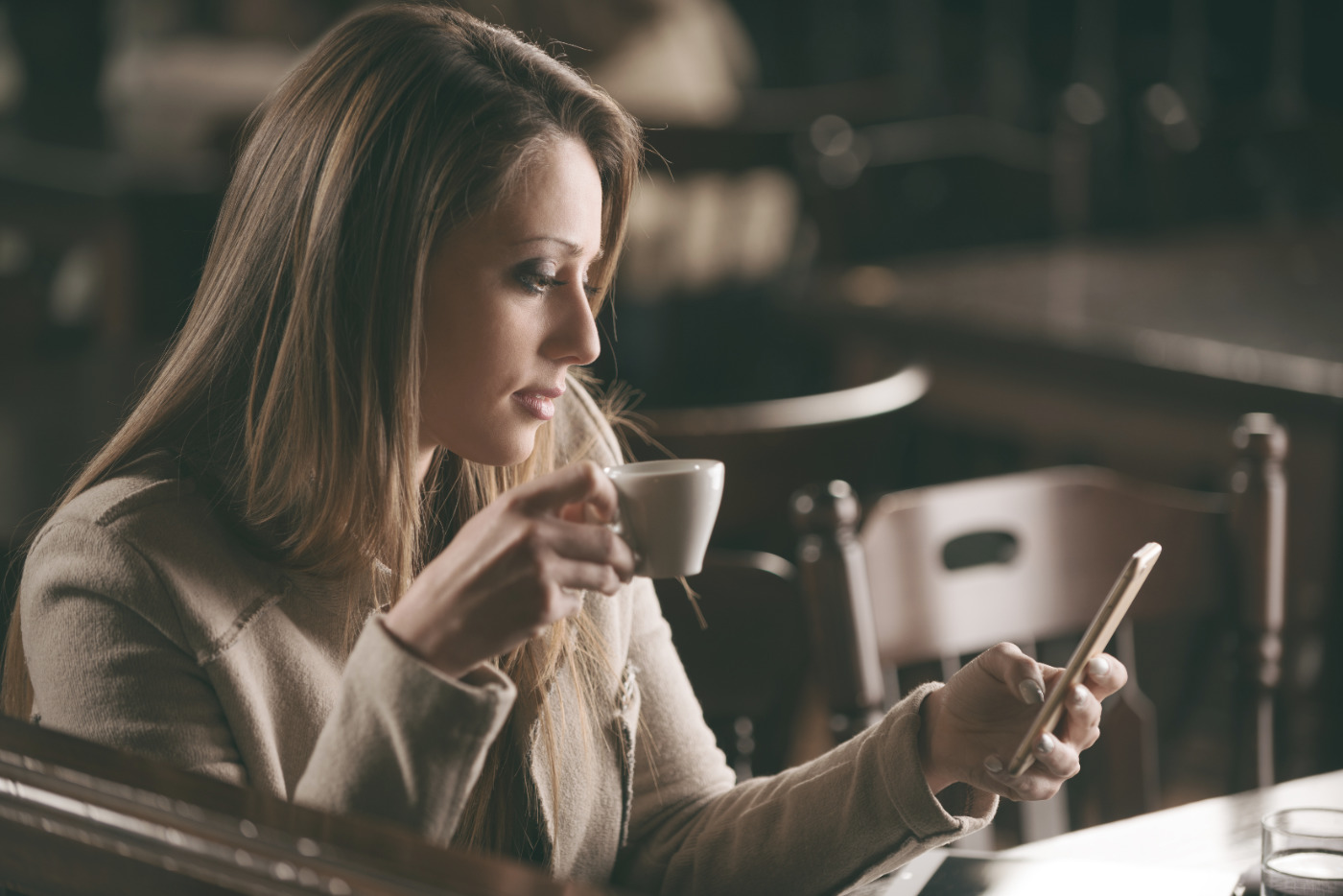 Woman drinking coffee while browsing on mobile device