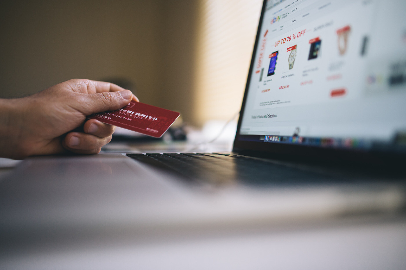 Hand holding credit card before computer screen