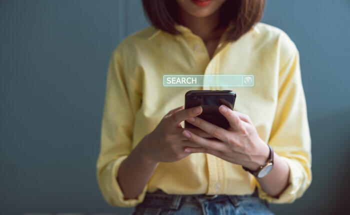 Woman using mobile device with glowing search bar on top