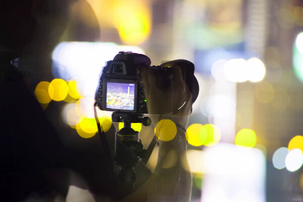 A professional videographer taking a video of a city at night