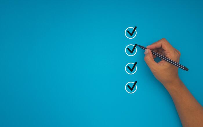 Close-up of hand holding a pen, checking off items in a checklist