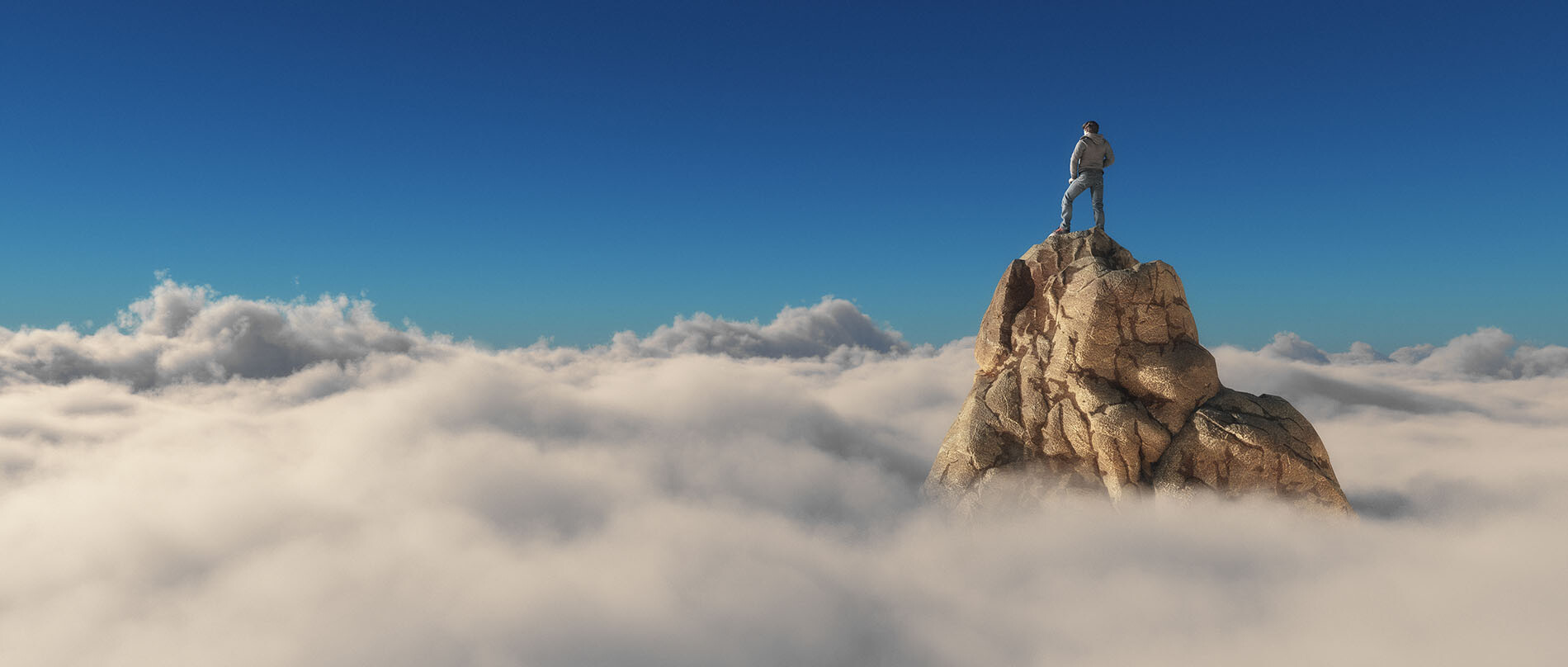 Person standing on mountain peak overlooking clouds