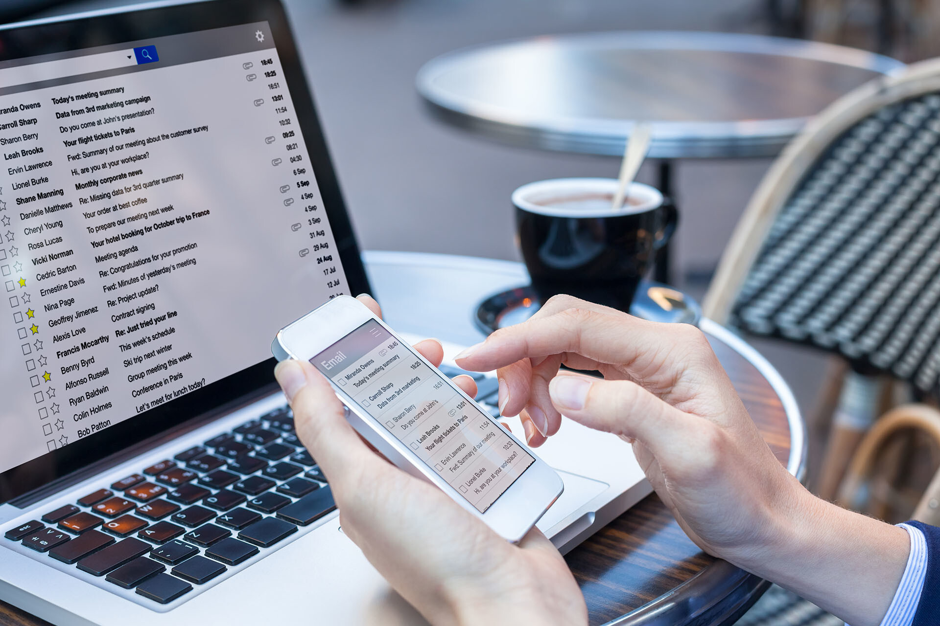 Person checking email on mobile device and laptop