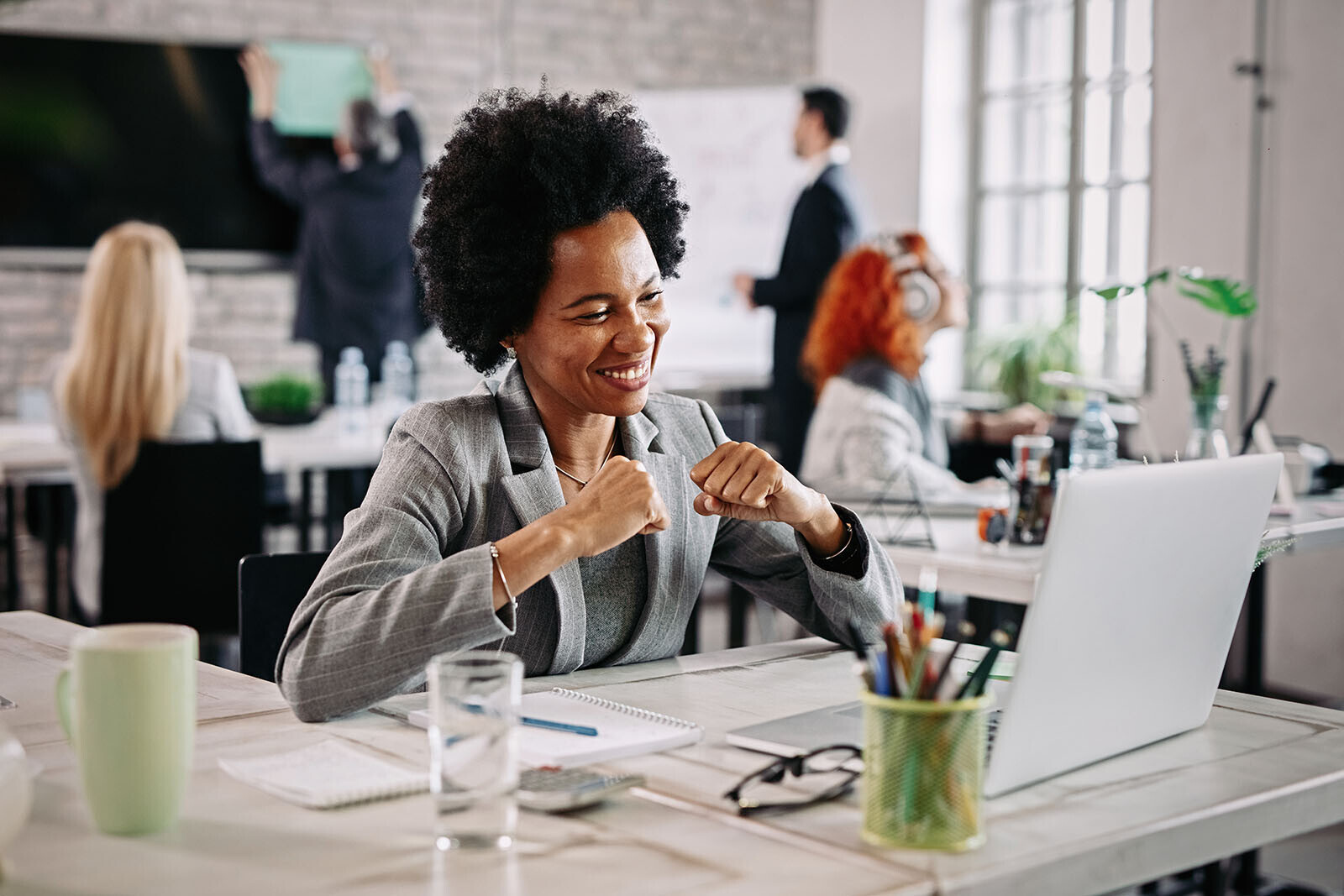 Satisfied customer celebrating in front of laptop in shared workspace